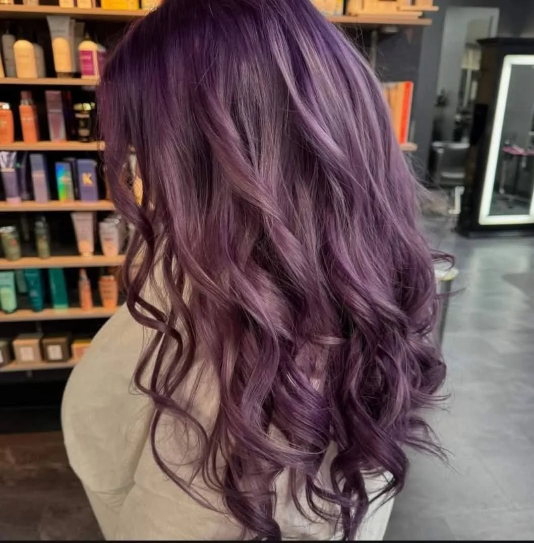 A person with long, wavy purple hair extensions in at Misfits Salon Alaska.