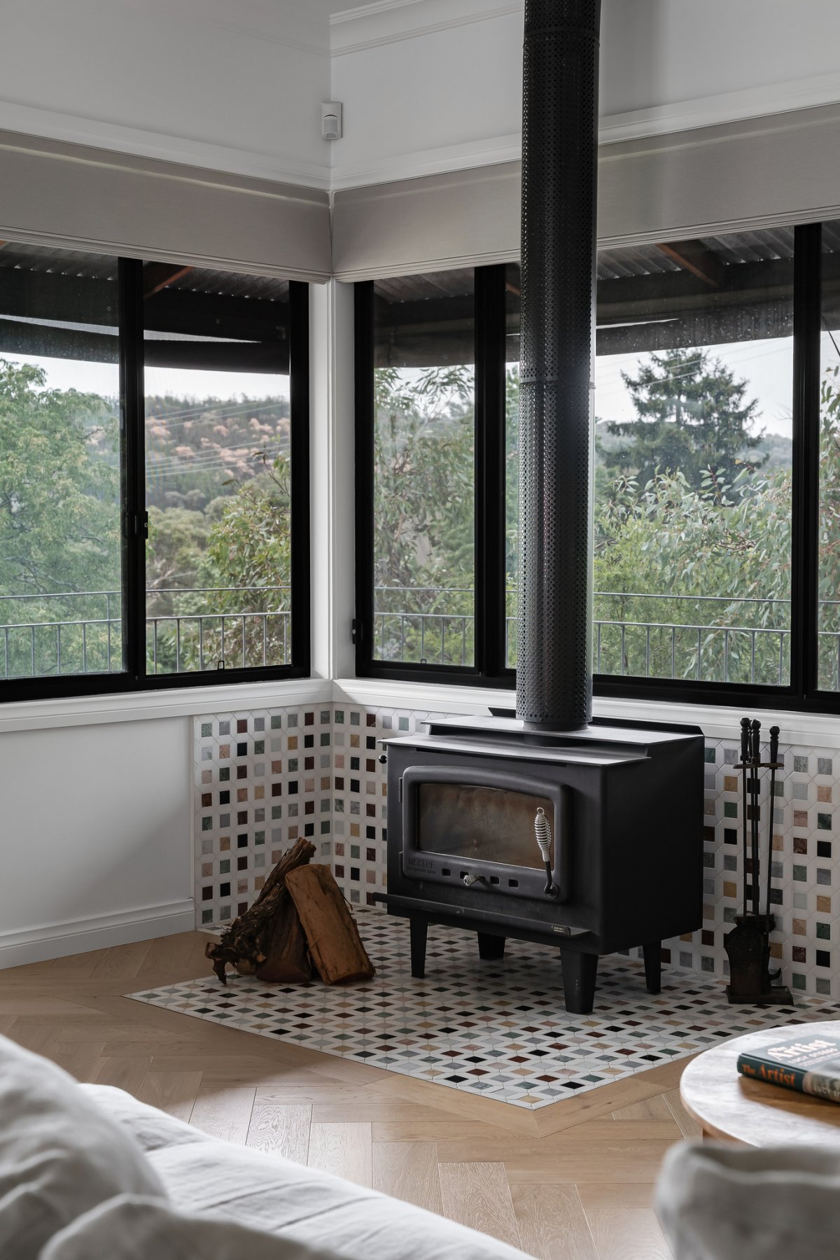 Echoing design language and materials from the adjoining kitchen, the fireplace hearth features new mosaic tiles.
