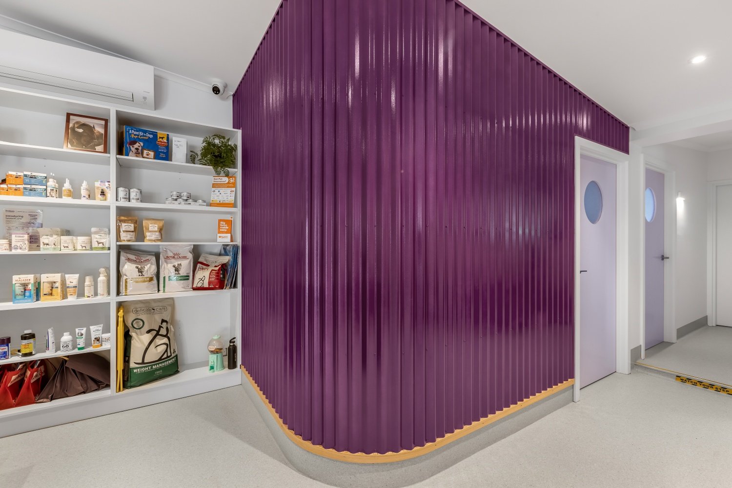 Curved orchid purple corrugated iron wall and merchandise area at Alpine Animal Doctors