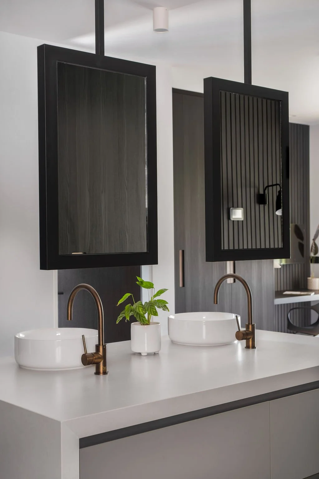 A central plinth vanity with floating steel-framed mirrors sits at the heart of the suite bathroom.