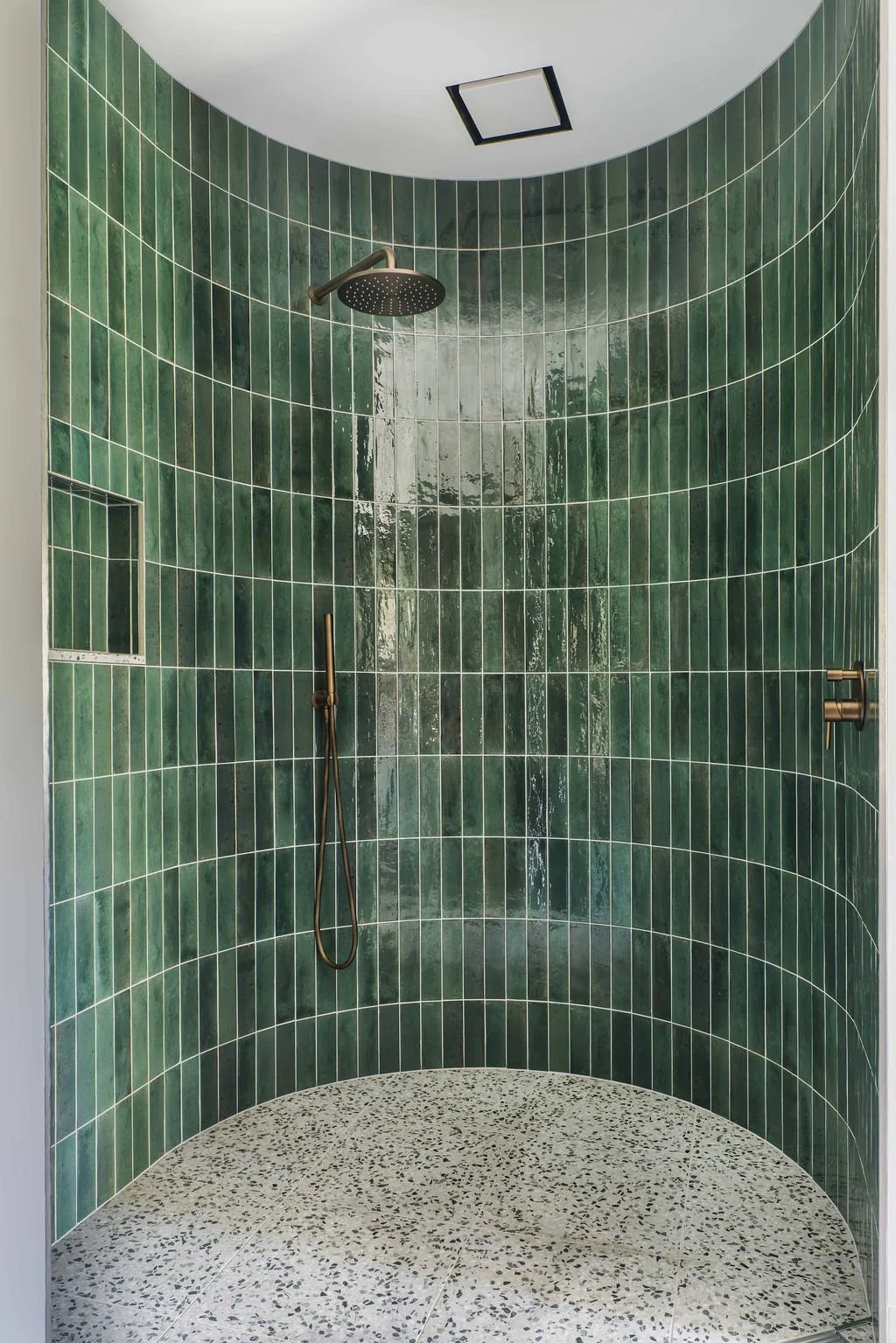 The main suite bathroom's masterpiece - a curved shower in emerald green tiles and terrazzo flooring.