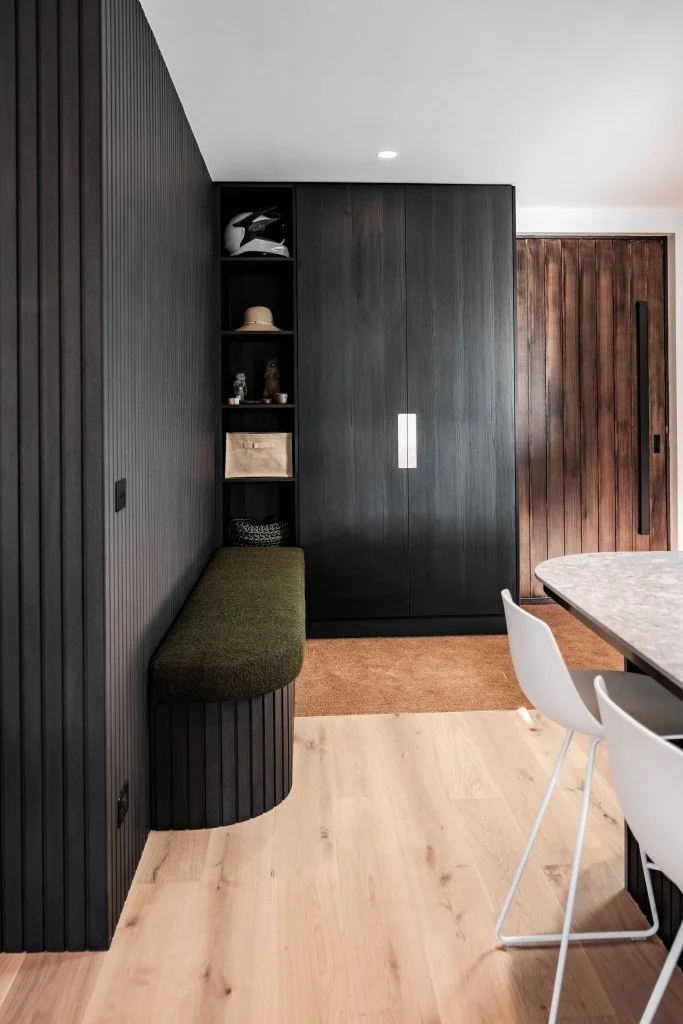 The new entry, featuring custom cabinetry and a bech seat, as seen from the kitchen.