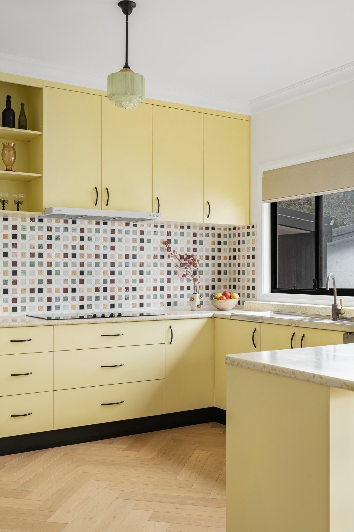 The existing yellow kitchen joinery formed the heart of the brief, with a new mosaic splashback added.