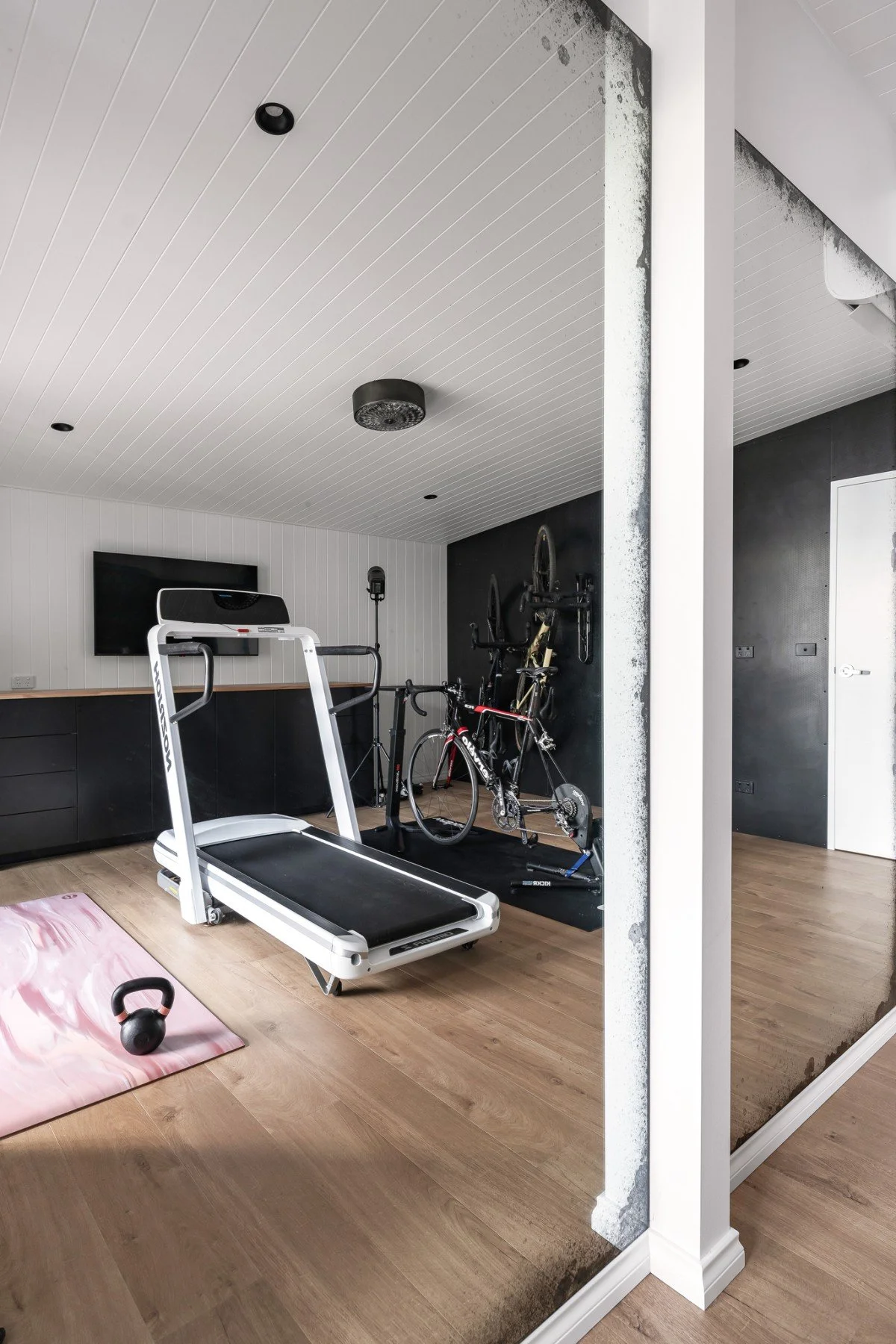 The bike and yoga studio features training equipment, storage, a stationary training set up, weights and a wall of floor to ceiling antique mirrors.
