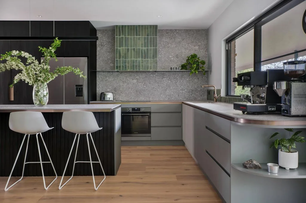 The kitchen features an Infinity Milan Stone porcelain bench top and splash to the ceiling, custom joinery in Oasis green, and a bronze-gold shadowline. 