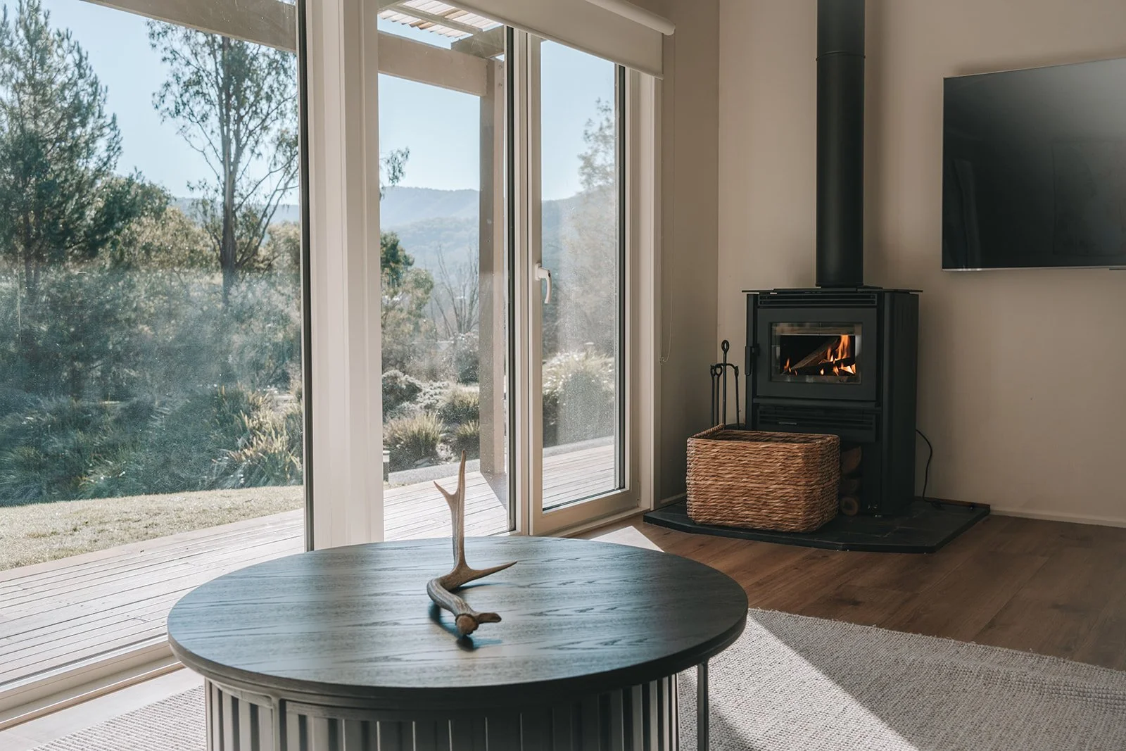 Alpine Gum living room with a wood burning fireplace, contemporary black coffee table and views towards the surrounding mountains.