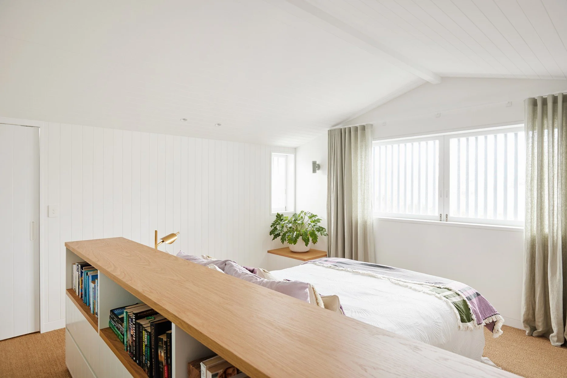 The bed in the main suite at High Tide is anchored by custom joinery, with ocean views beyond