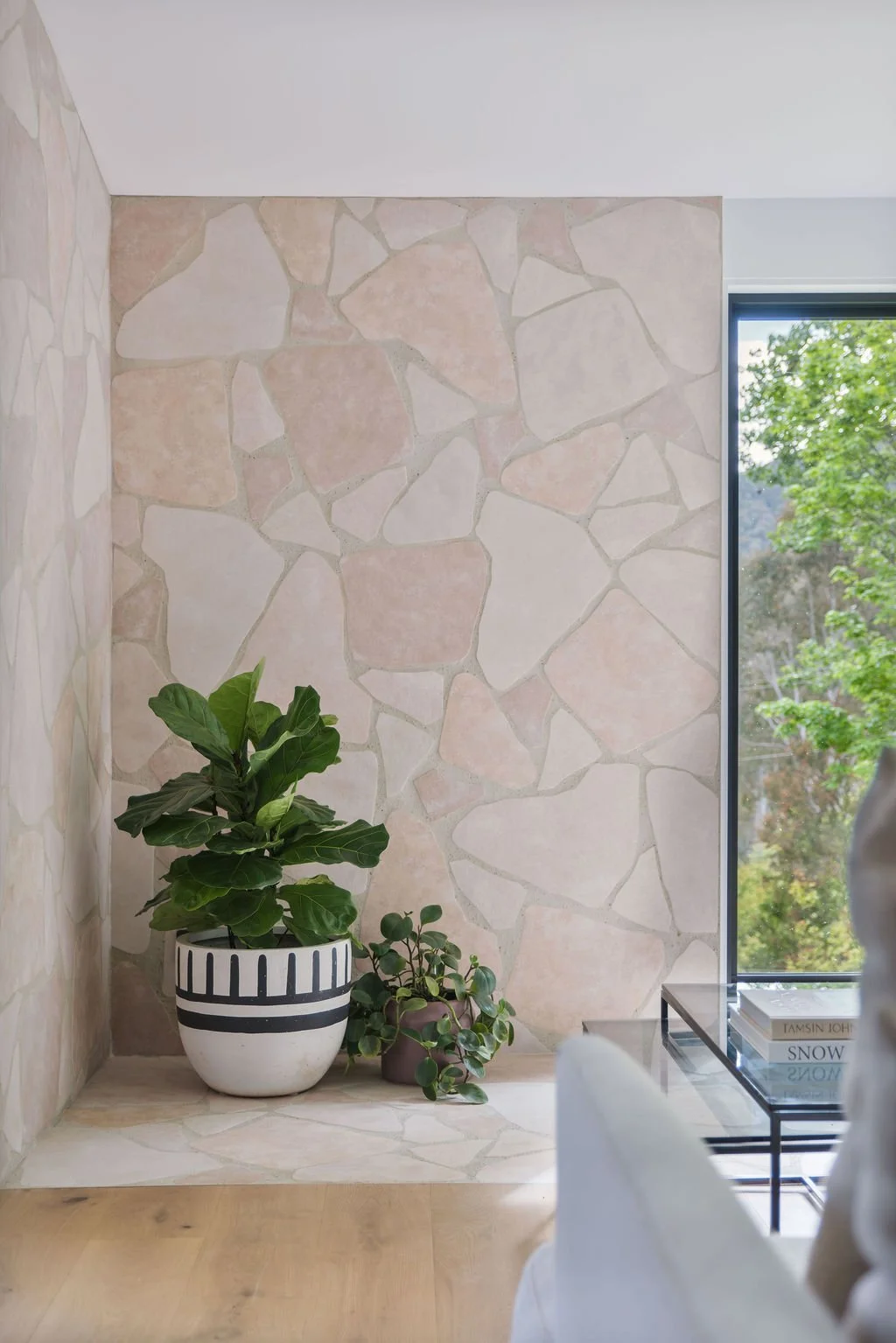  A stone-paved hearth anchors the lounge, creating a warm focal point against the surrounding greenery.
