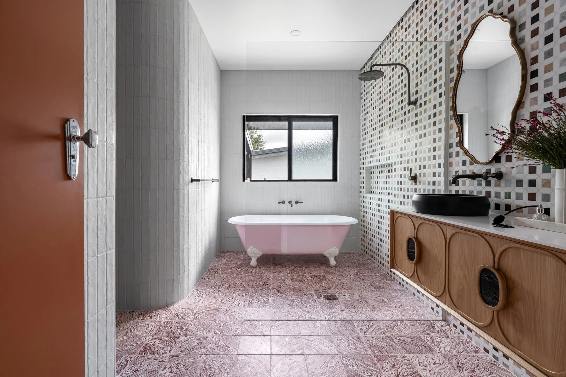 The main bathroom is a room of real presence, with a pink clawfoot bath, expressive tiles, gold ornate mirror,  American oak Zuster vanity and concrete basins.