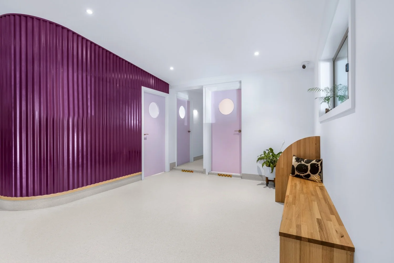 Veterinary waiting area with lavendar wooden doors with frosted glass porthole doors beyond