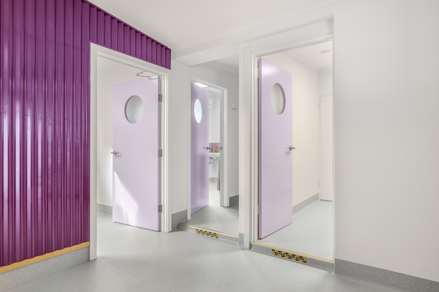 Wooden porthole doors in lavender with frosted glass lead to the consult rooms in a regional veterinary practice