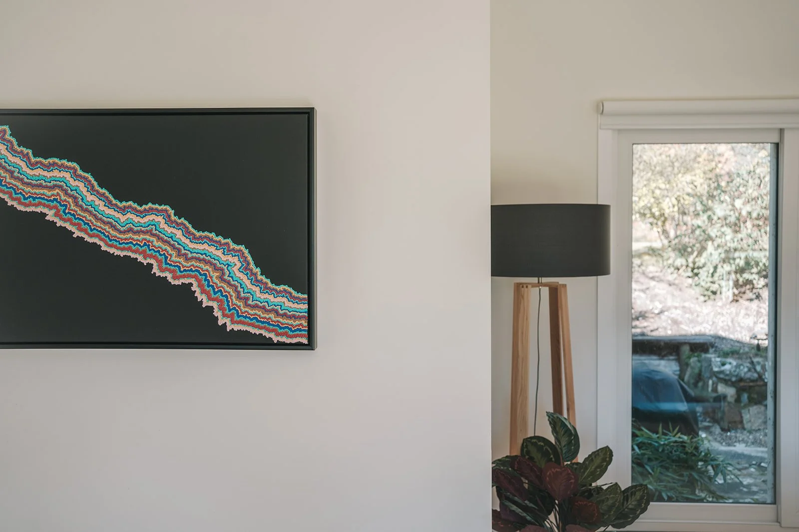 Colourful contemporary artwork displayed alongside a timber floor lamp, connecting Alpine Gum's interior palette with its natural surroundings.
