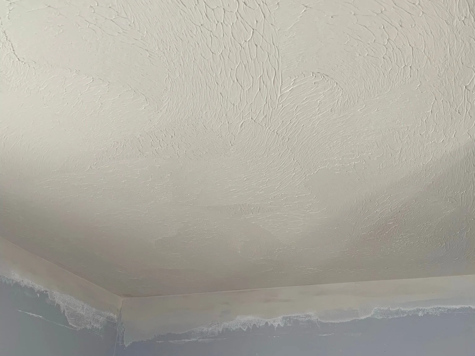 Ceiling with textured drywall finish and border paint where the wall meets the ceiling.