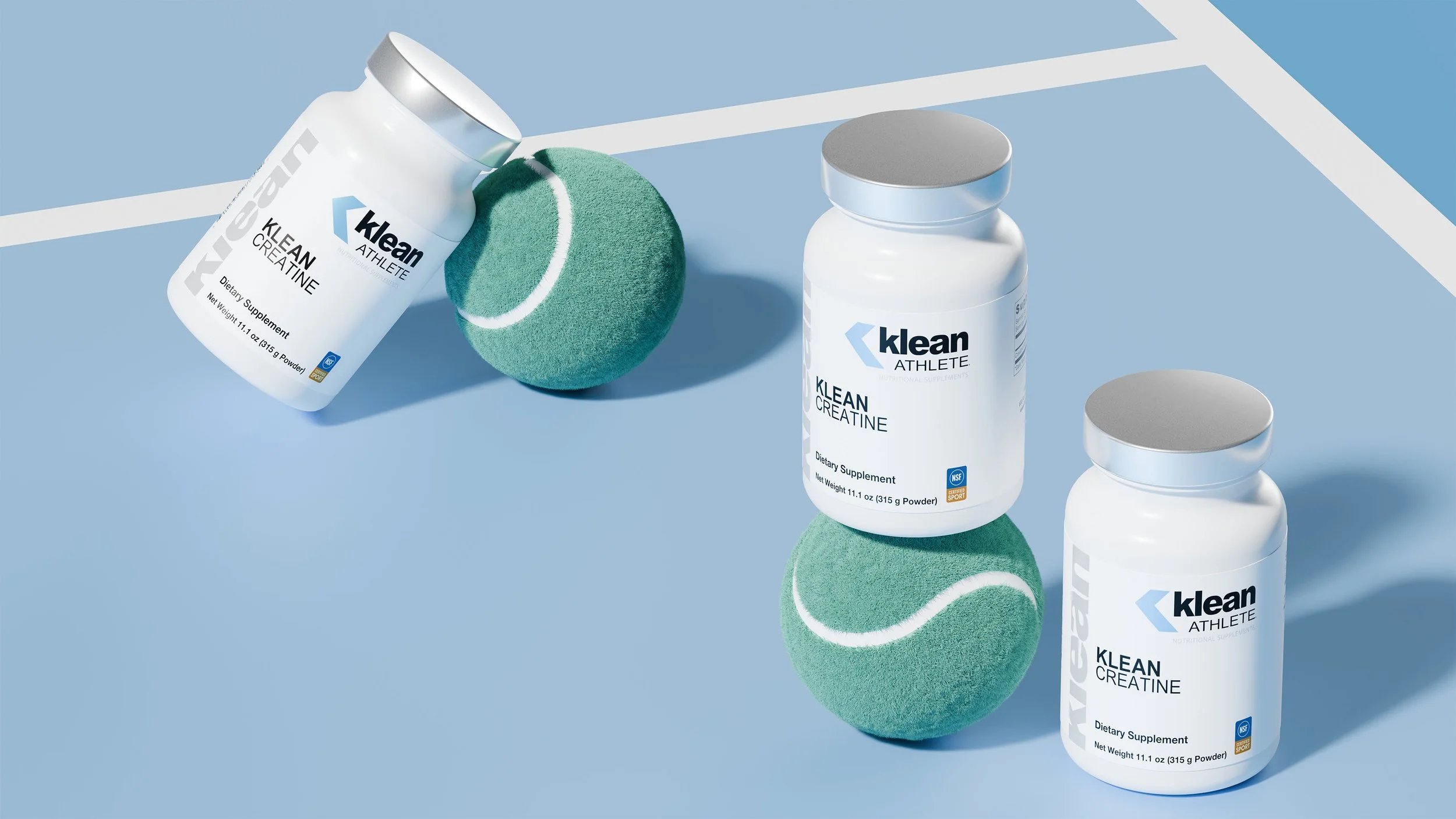 Three white bottles of Klean Athlete creatine dietary supplement on a light blue surface, with two green tennis balls in between and a tennis court edge in the background.