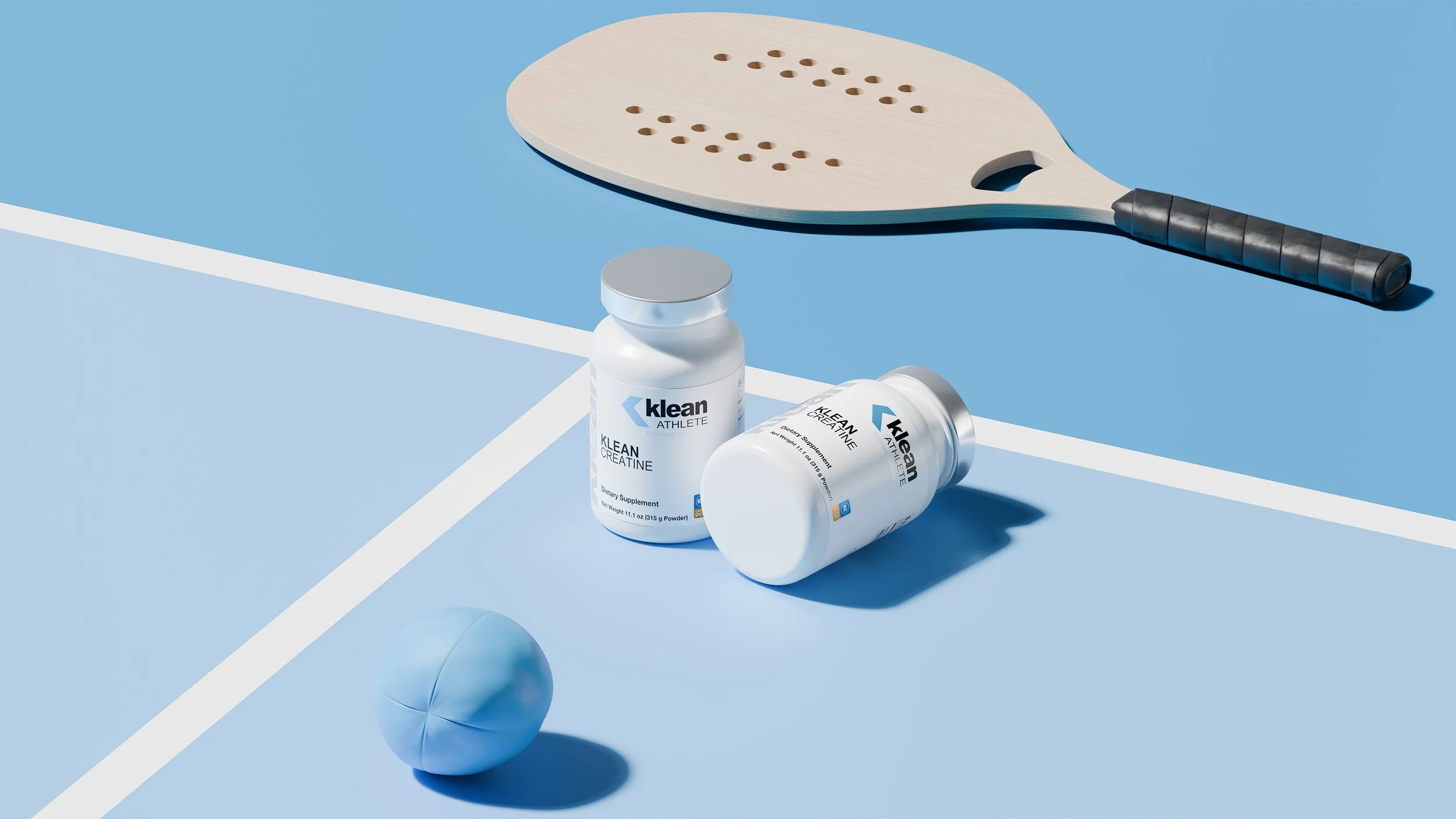 Two bottles of Klean Athlete dietary supplements, a blue tennis ball, and a wooden paddle on a blue tennis court.
