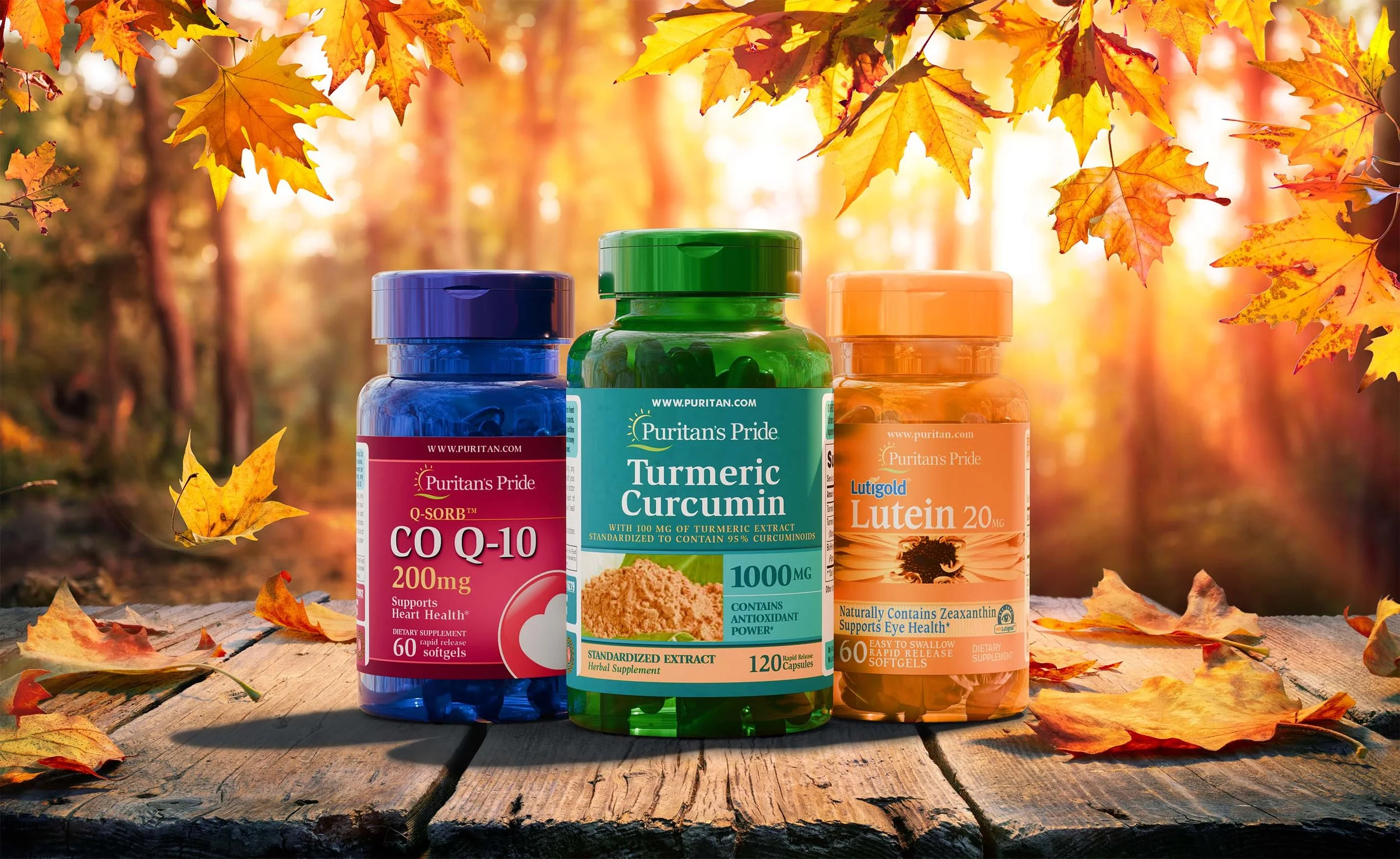 Three bottles of dietary supplements from Puritan's Pride placed on a wooden surface with autumn leaves, by a sunlit woods background.