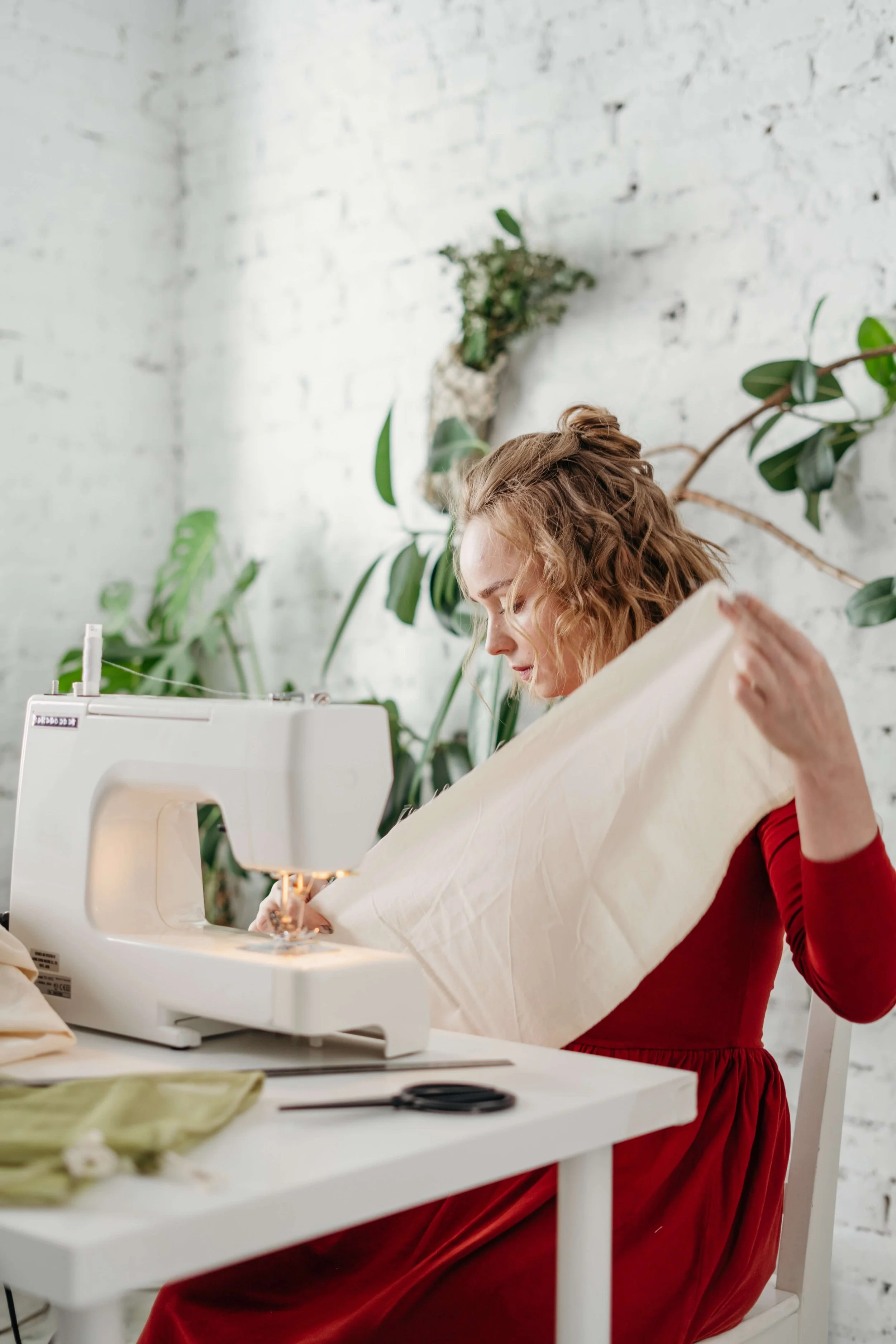 white sewing machine and female sewist in red
