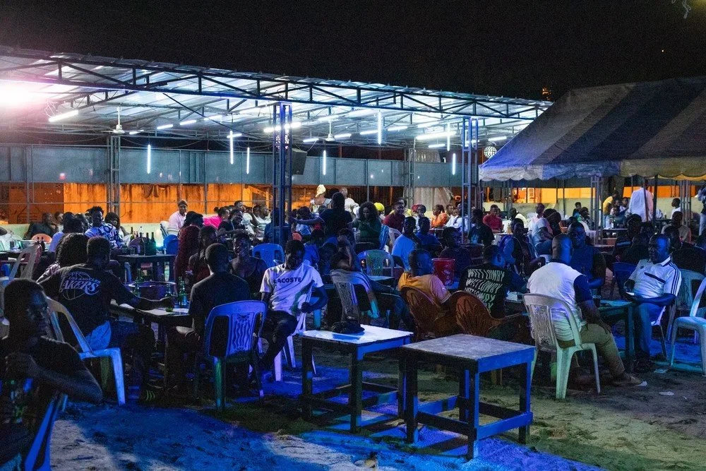 Audience gathered around tables during a live zouglou performance in Yopougon, Abidjan