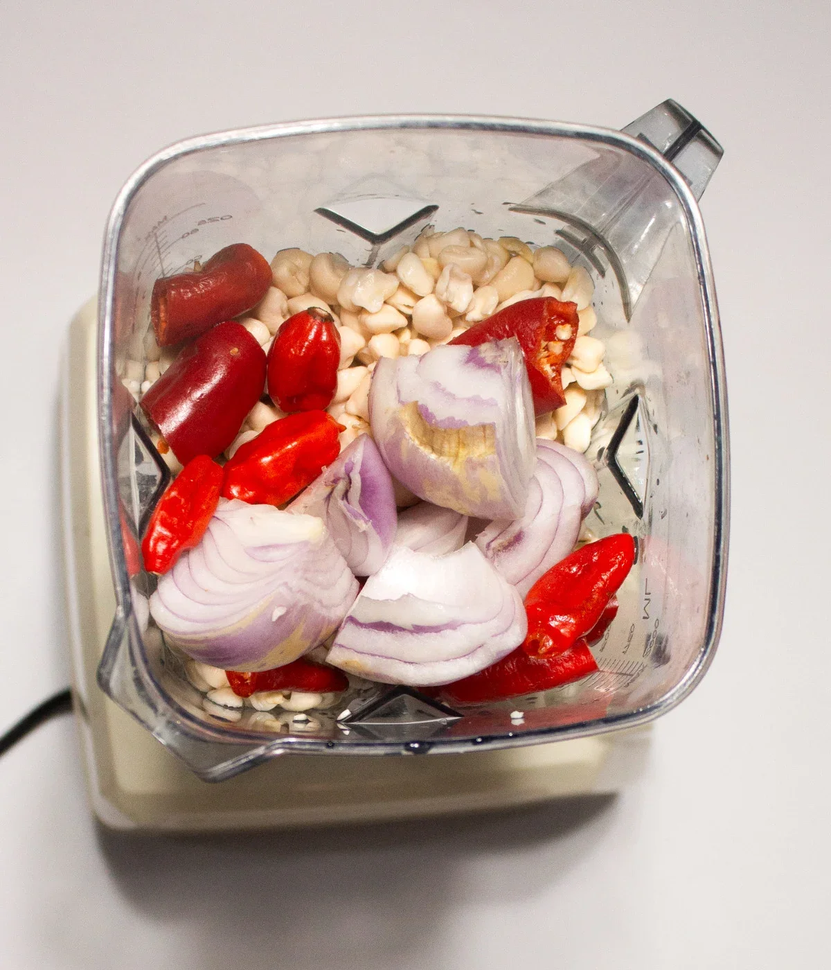 Peeled-beanse-onion-red-bell-pepper-scotch-bonnets-in-a-blender.webp