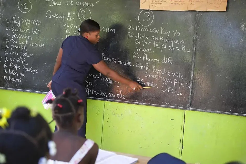 Haitian students taking notes during a Creole class at Louverture Cleary School in Haiti.