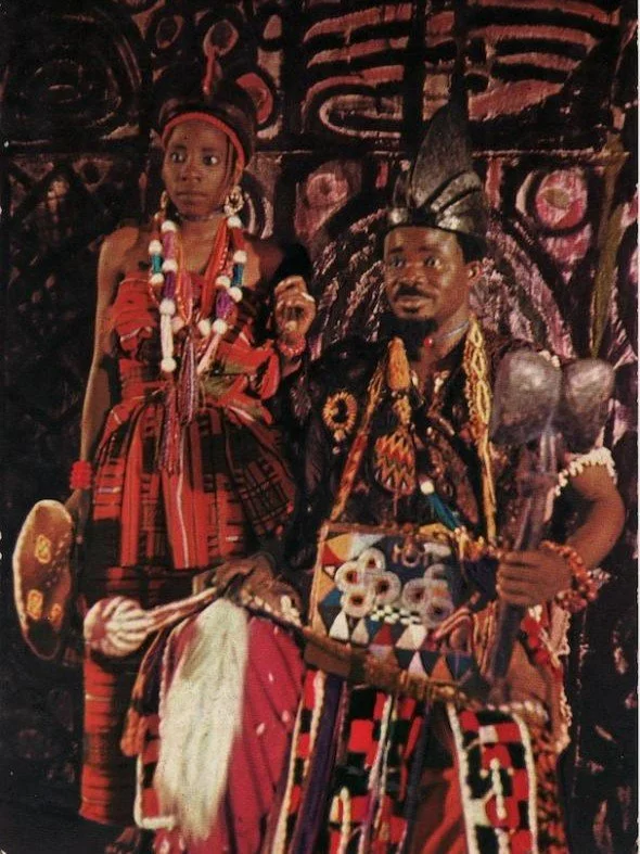 Abiodun Ladipo in theatrical costume standing before Georgina Beier’s painted backdrop for Duro Ladipo’s theatre group.