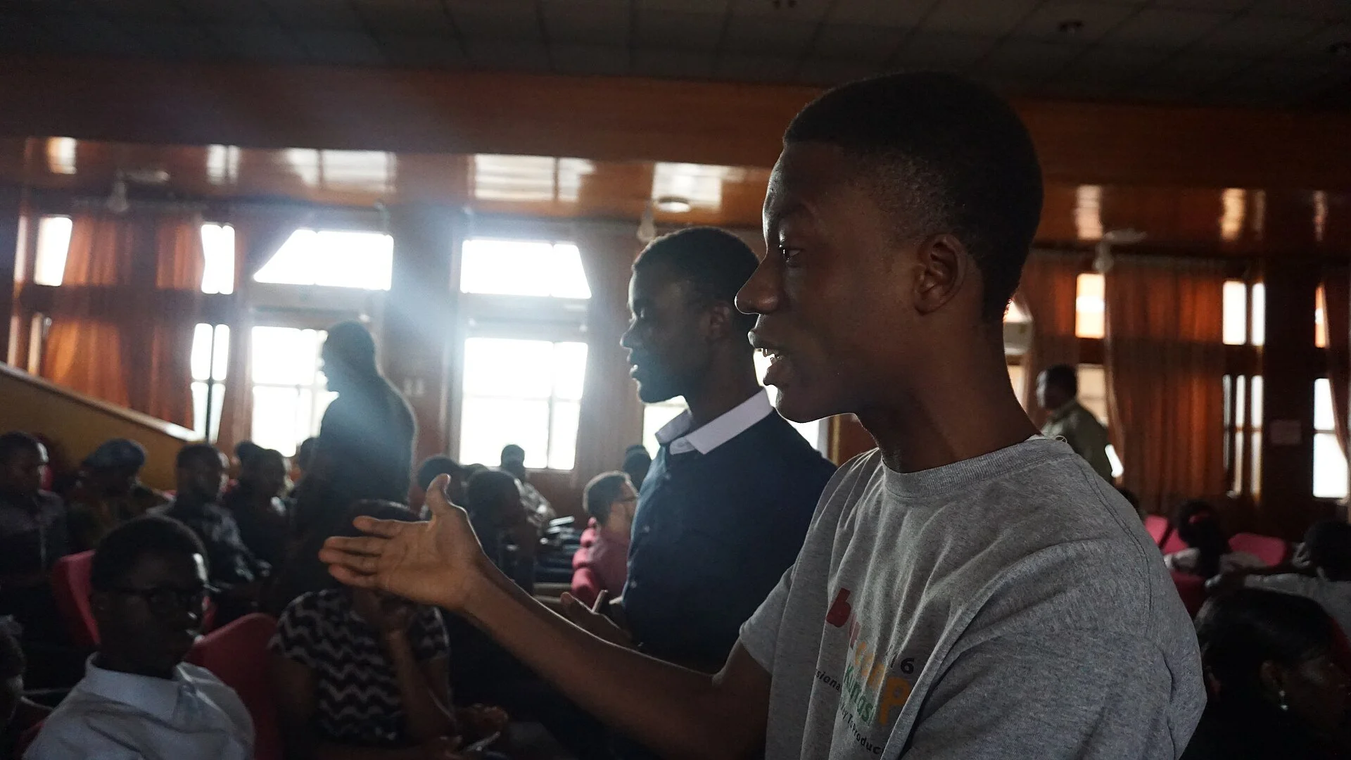 Young Ghanaian man gesturing with an open hand while speaking during a group discussion in Kumasi