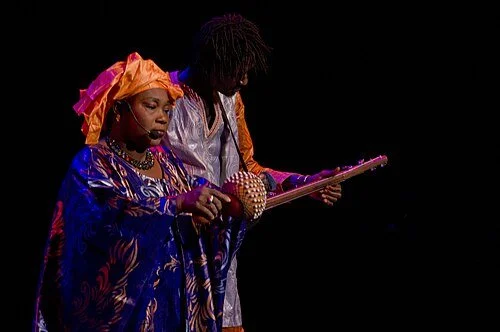 Female vocalist from Trio Da Kali performing beside a musician playing the ngoni in Mexico City in 2016