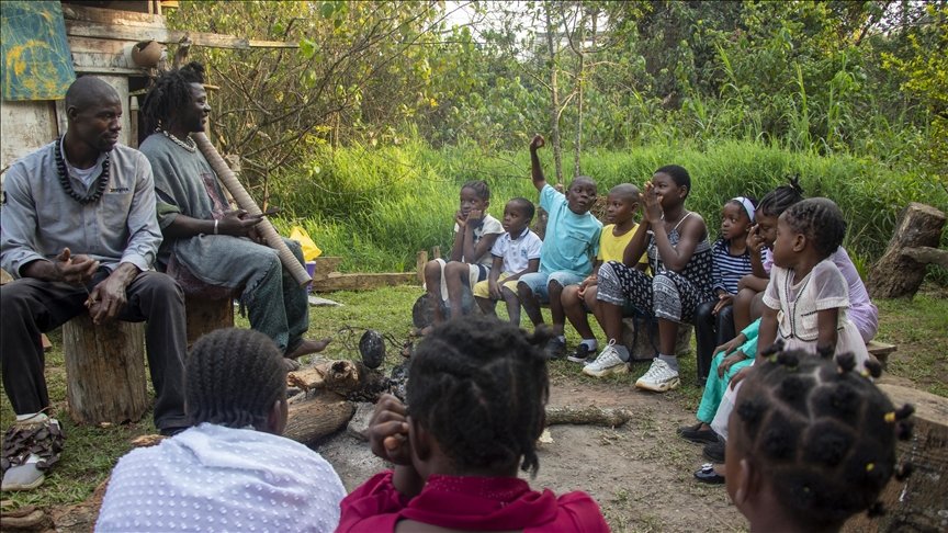 Cameroonian griot telling stories to children in an outdoor gathering.