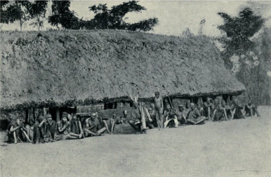 Eze Nri Obalike seated on a carved stool and ringing a bell in an early twentieth-century photograph