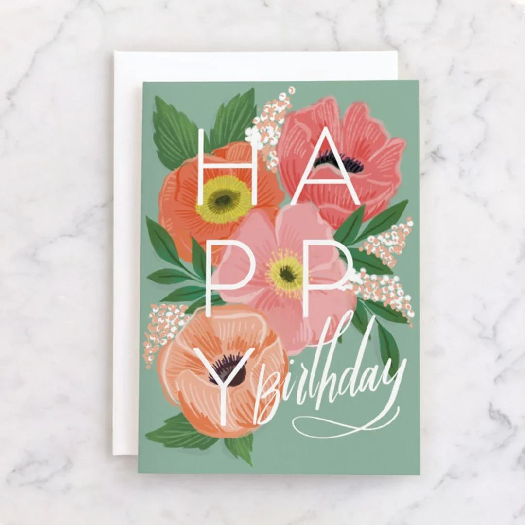 Birthday greeting card with a floral design featuring pink, orange, and peach flowers with green leaves, and the words 'Happy Birthday' in white cursive and block letters.