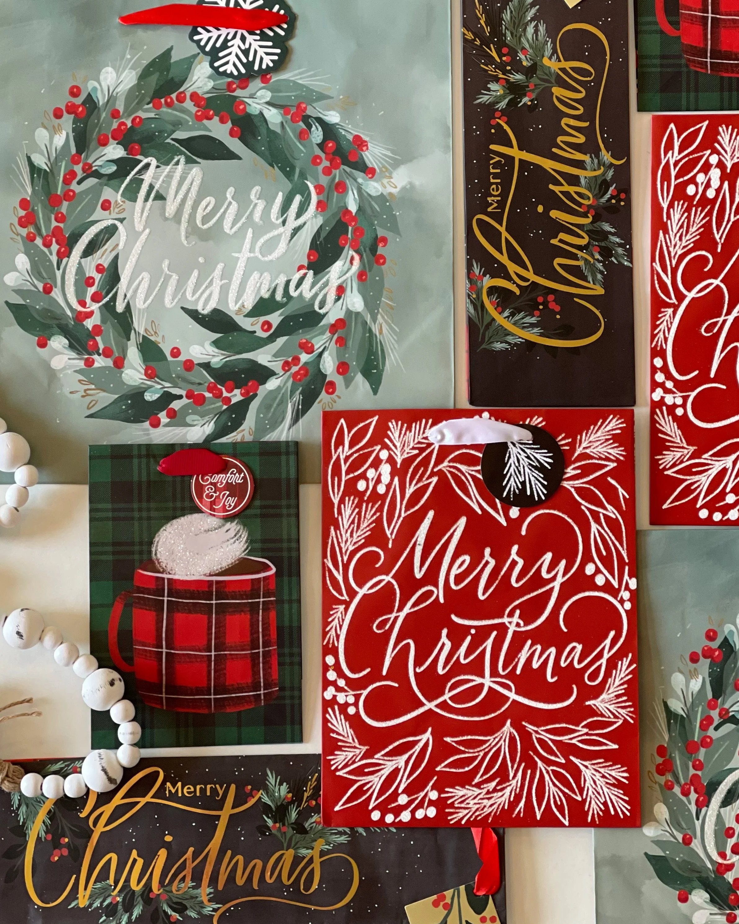 Collection of Christmas cards with holiday greetings and festive designs, including wreaths, berries, pine leaves, a mug, and decorative lettering.