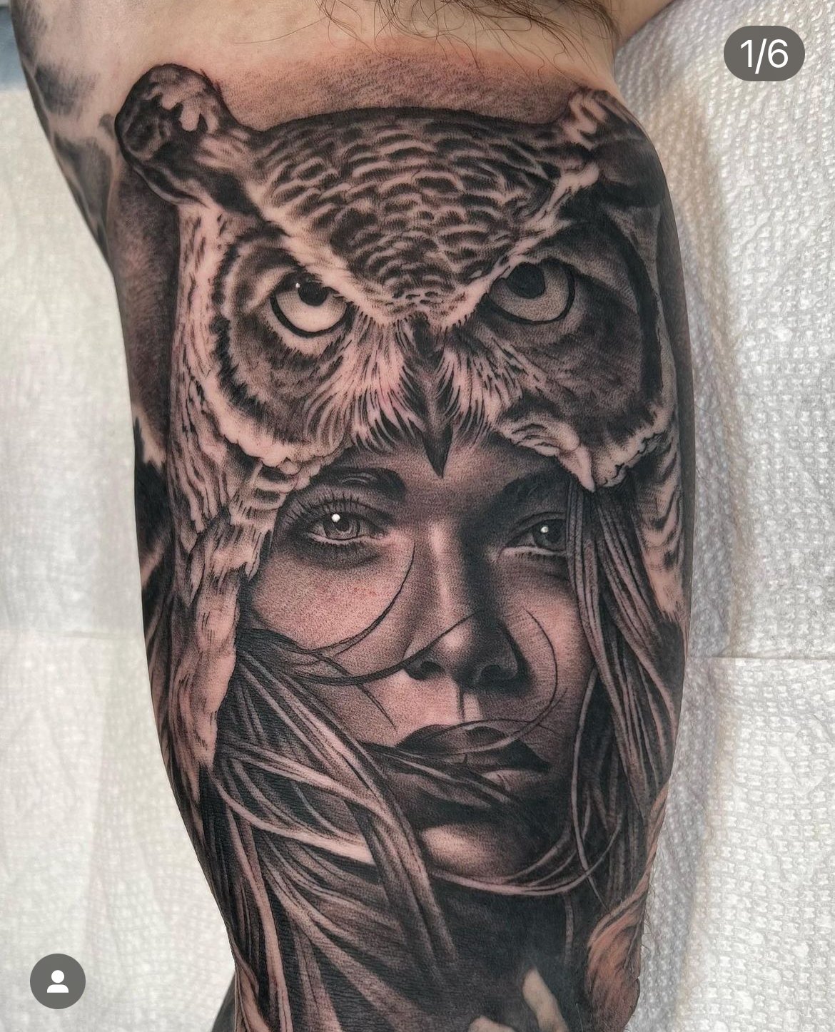 A black and gray tattoo of an owl with intense eyes above a woman's face with flowing hair.