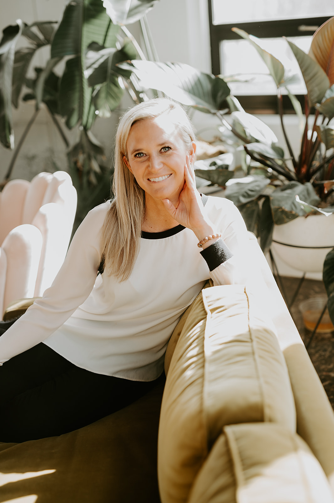 georgia sitting in a green chair smiling with plants around her