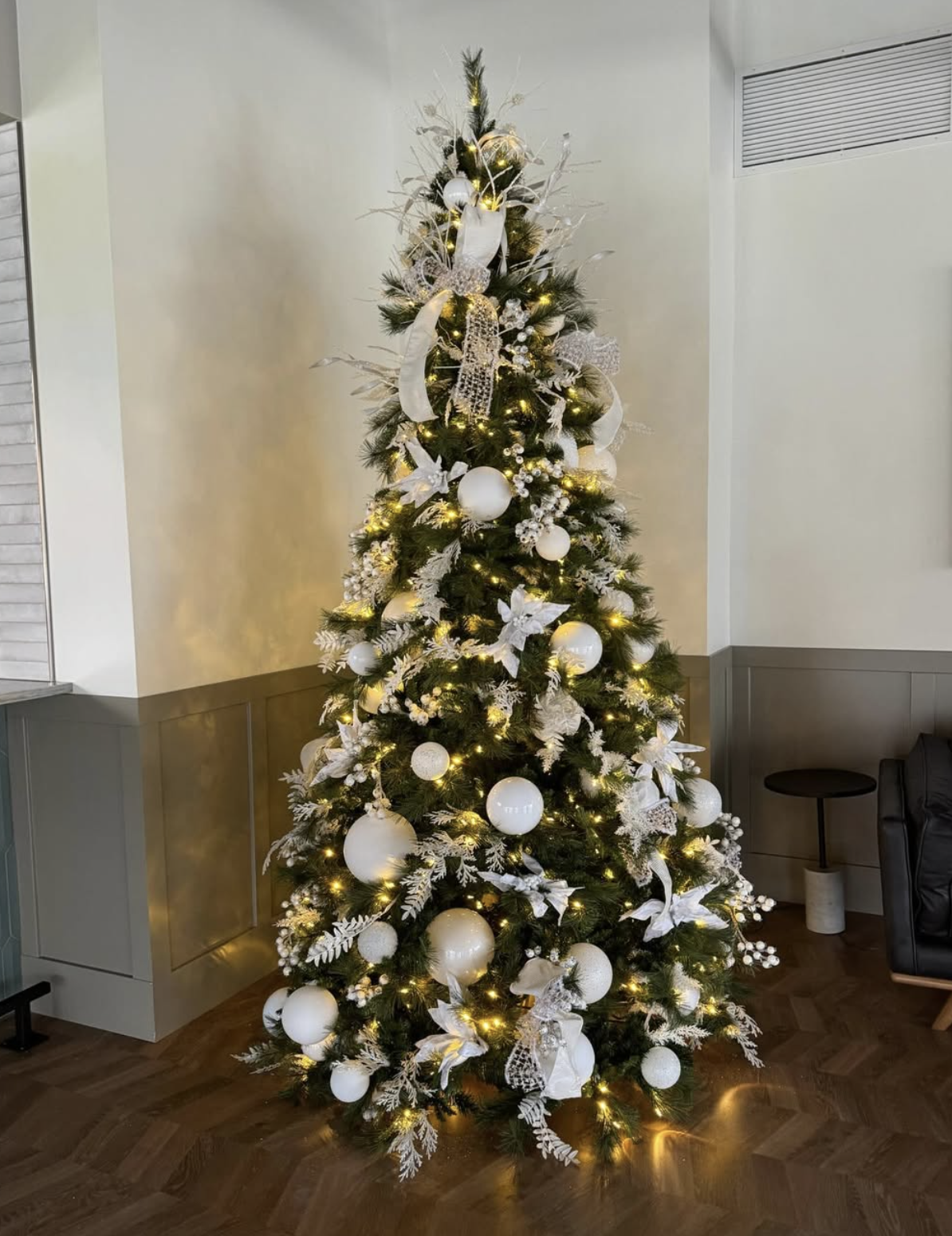 White and silver decorated Christmas tree with lights in an office lobby.