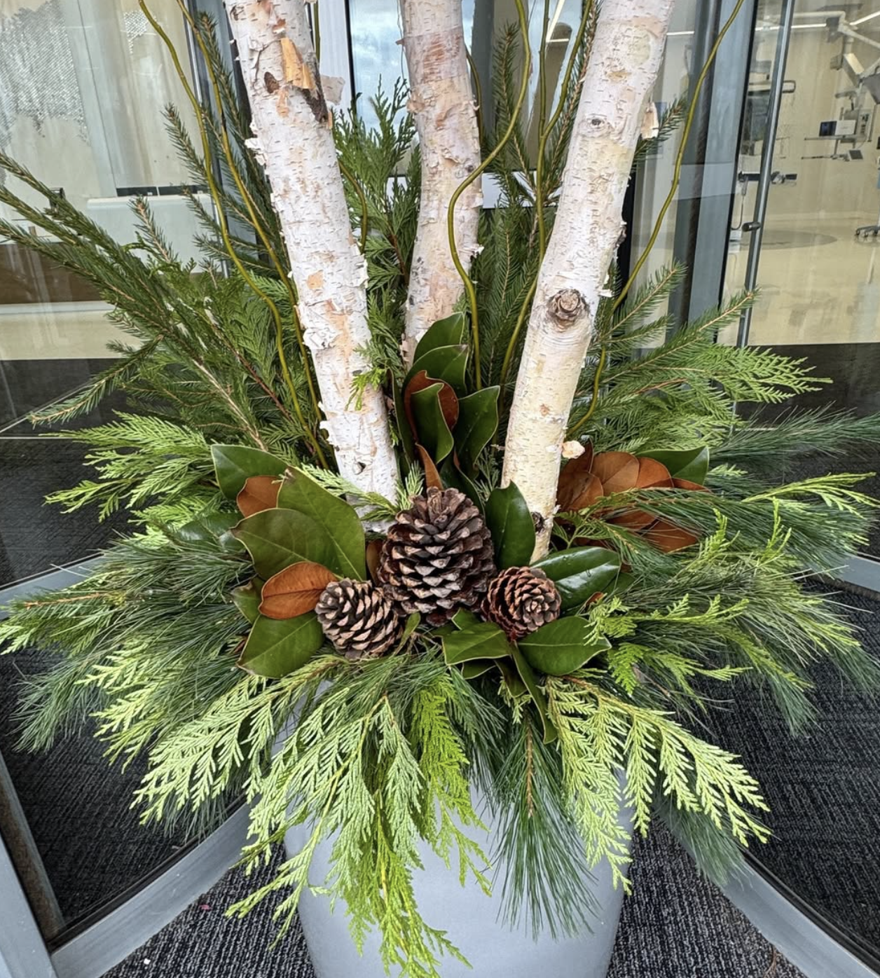 A holiday-inspired outdoor planter with garland and pinecones.