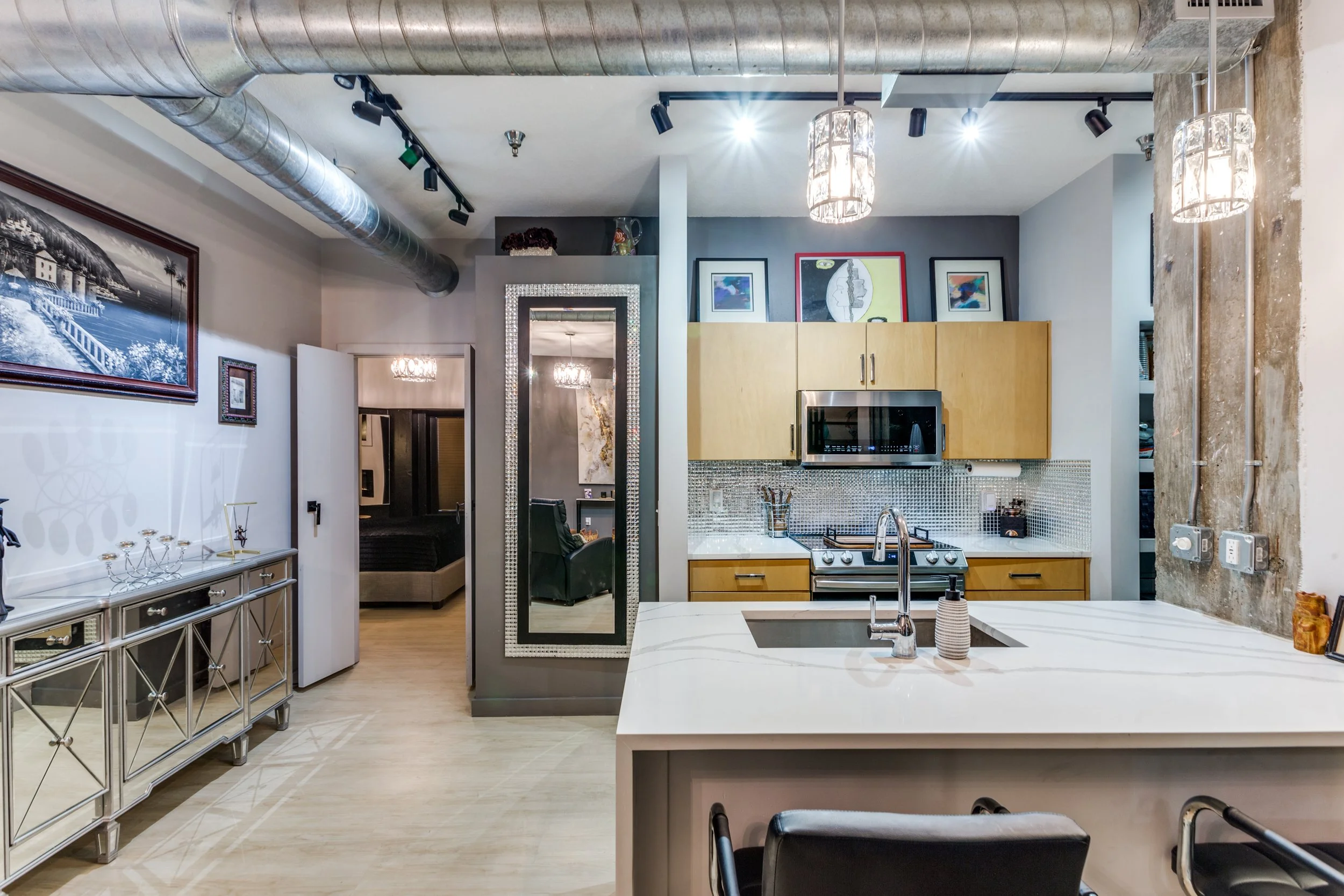 Modern kitchen with white marble island, yellow cabinets, stainless steel microwave, and decorative artwork on the walls.