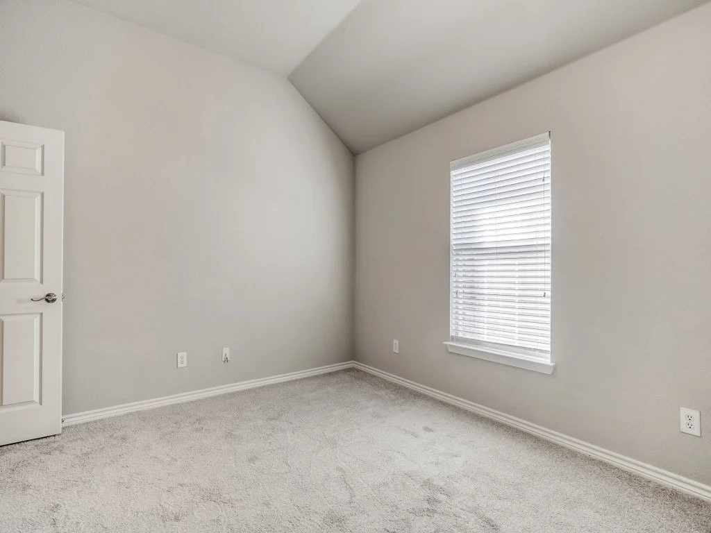 Empty room with a window, white blinds, and white walls.