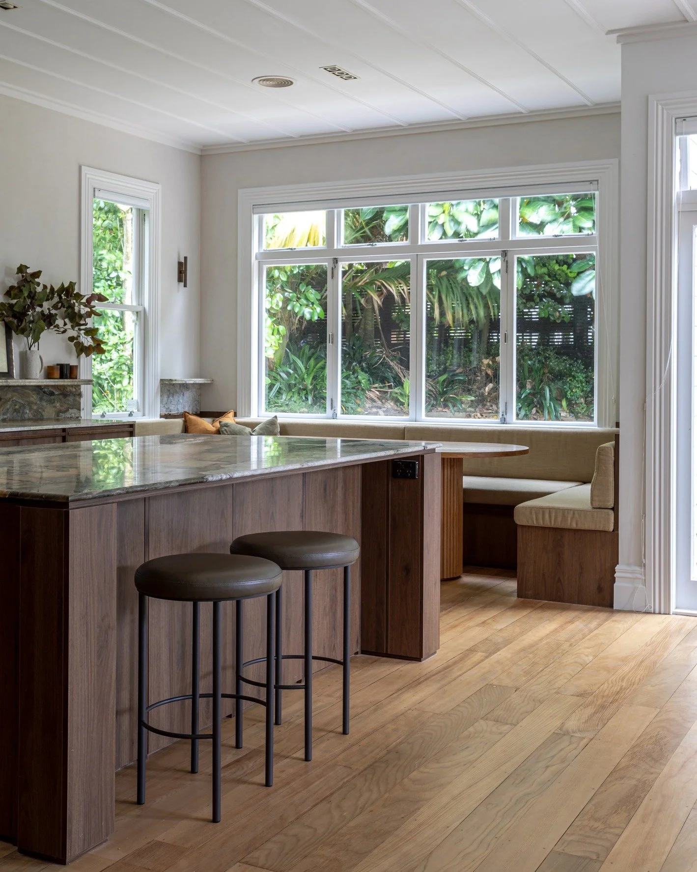 White walls, warm timber cabinetry and flooring, and a statement green marble benchtop.

This palette strikes a balance between clean and contemporary, while the natural materials add warmth, depth and character. It's a look that's proving popular in