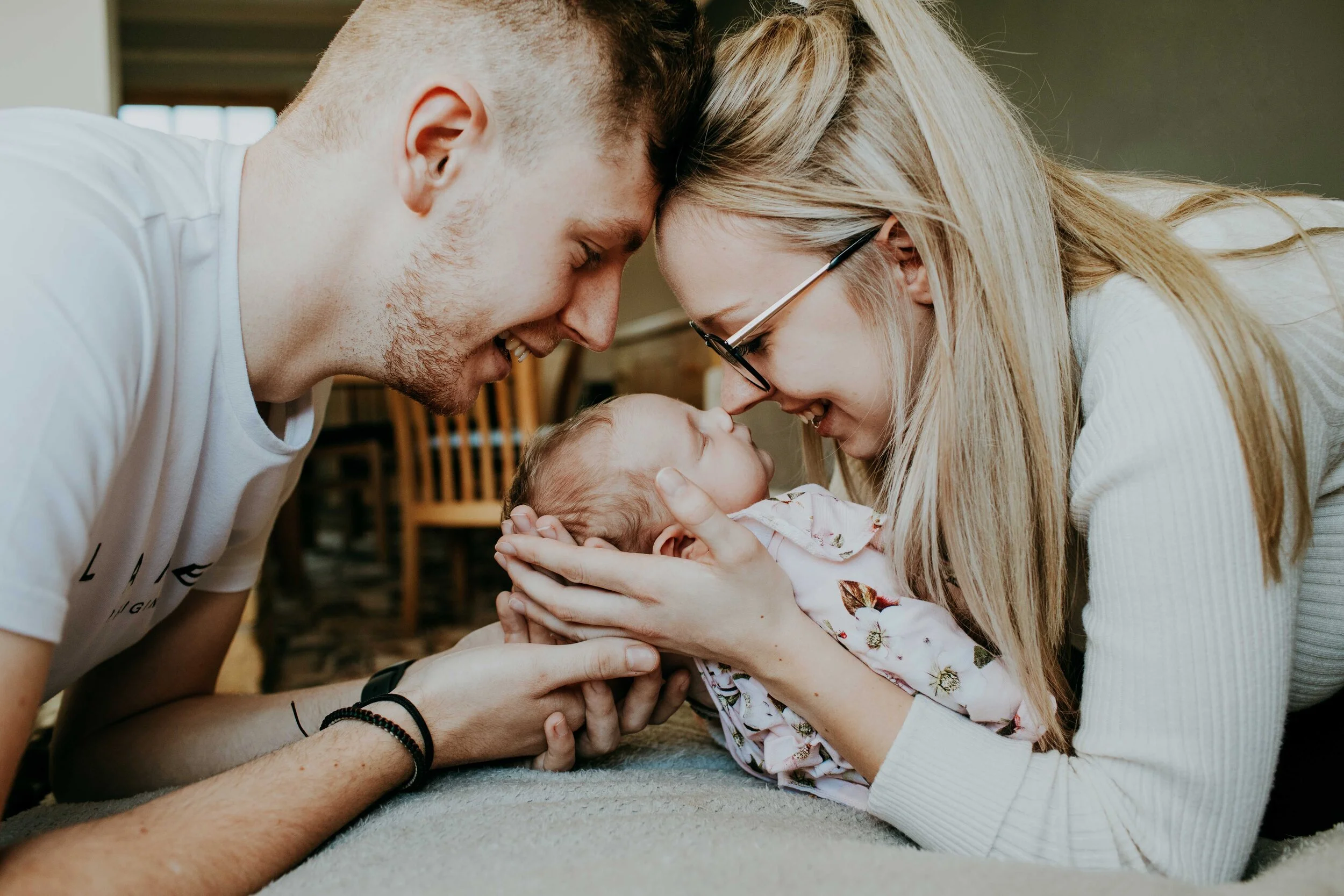 Parents lovingly holding and looking at their baby.