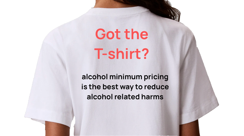 Back of a person wearing a white T-shirt with red and black text promoting alcohol minimum pricing.