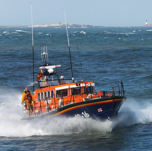 Rock formations and a heart-shaped arrangement made of stones on a beach near the ocean with overcast skies.