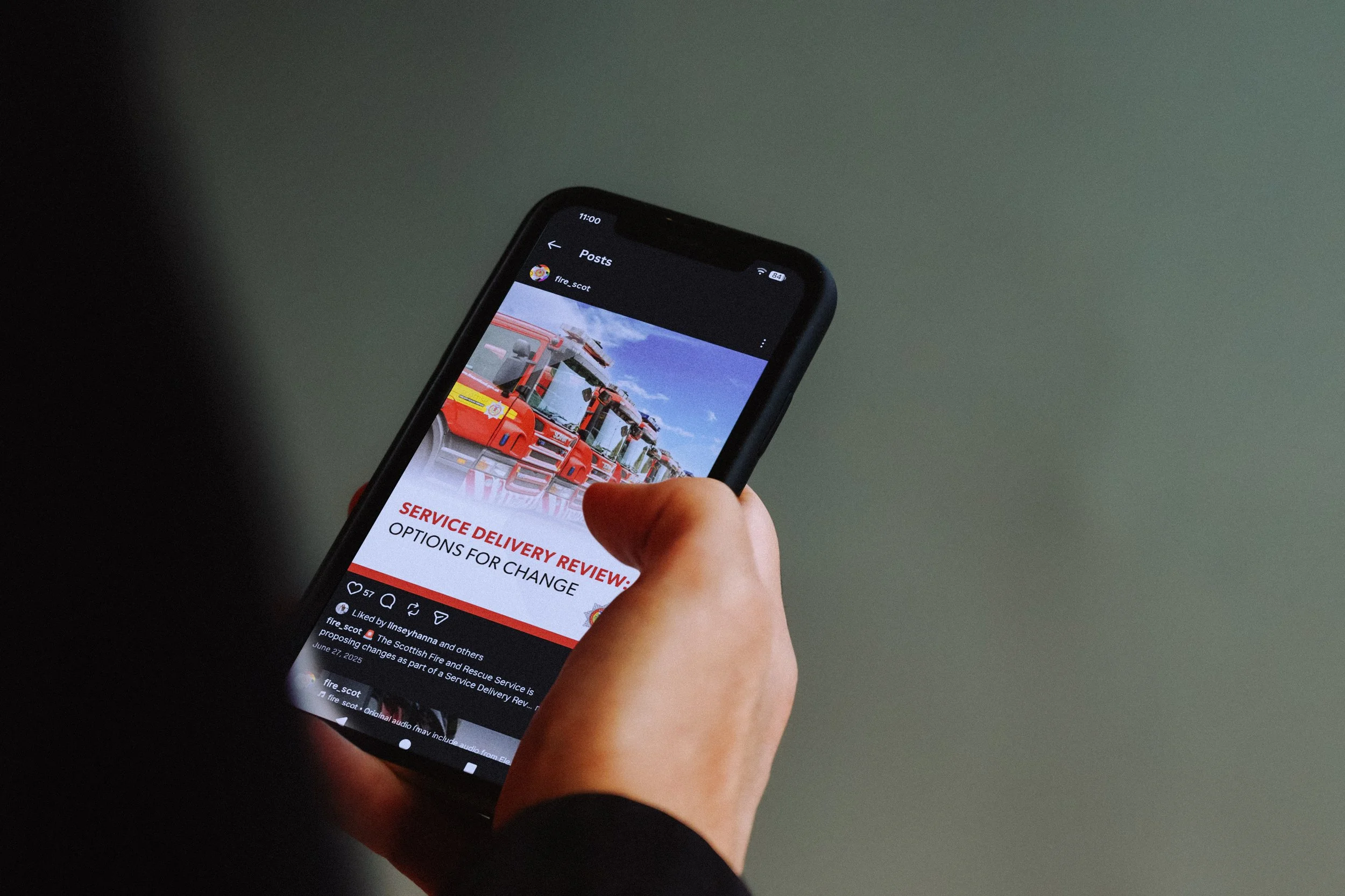 a man holding a phone looking at the SFRS Instagram social media account