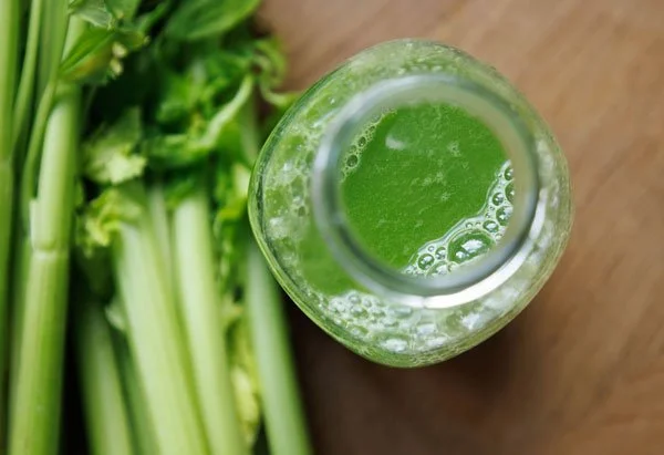 Glas Selleriesaft von oben, Sellerietangen im Hintergrund