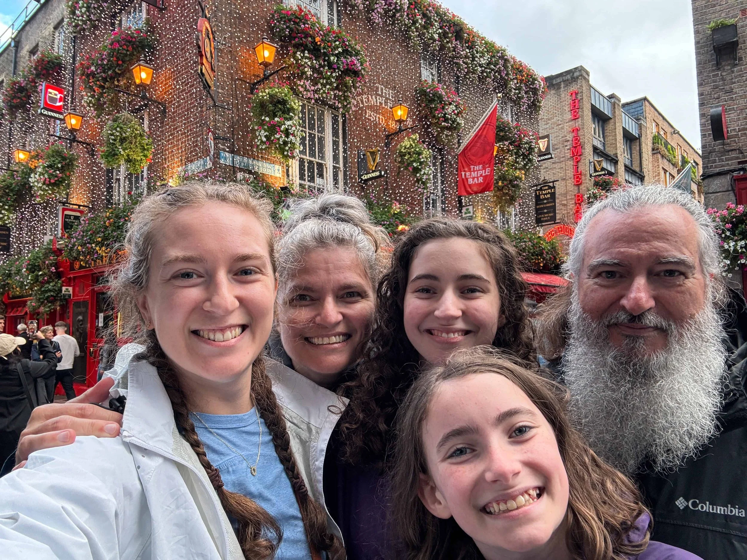Smiling family selfie in front of the colorful Temple Bar pub in Dublin, Ireland a joyful cultural moment embracing difference and connection during family travels and breaking free from societal expectations.