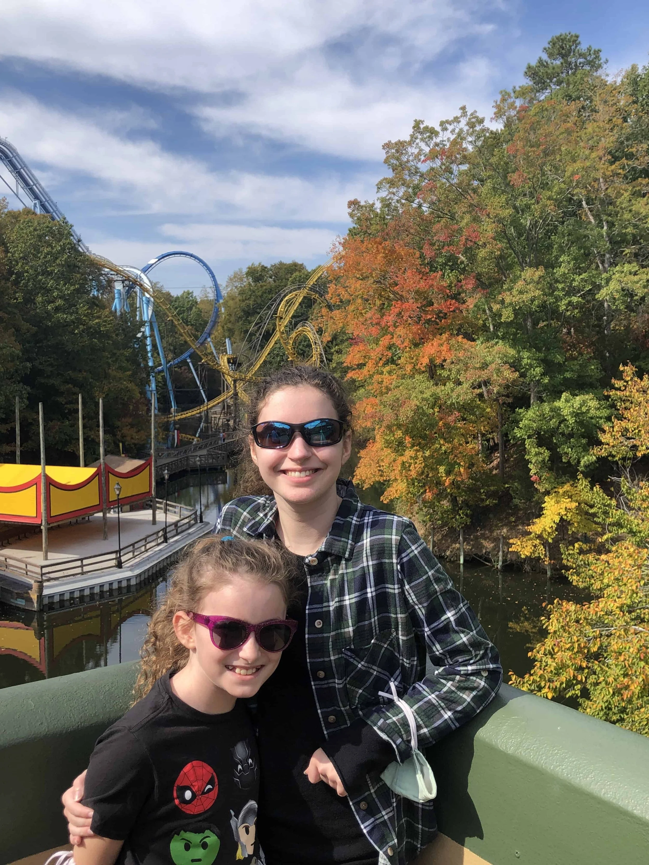 Sophie &amp; Rachel, posing in front of the river where three separate roller coaster tracks, Loch Ness Monster, Alpengeist, &amp; Griffon, can be seen.