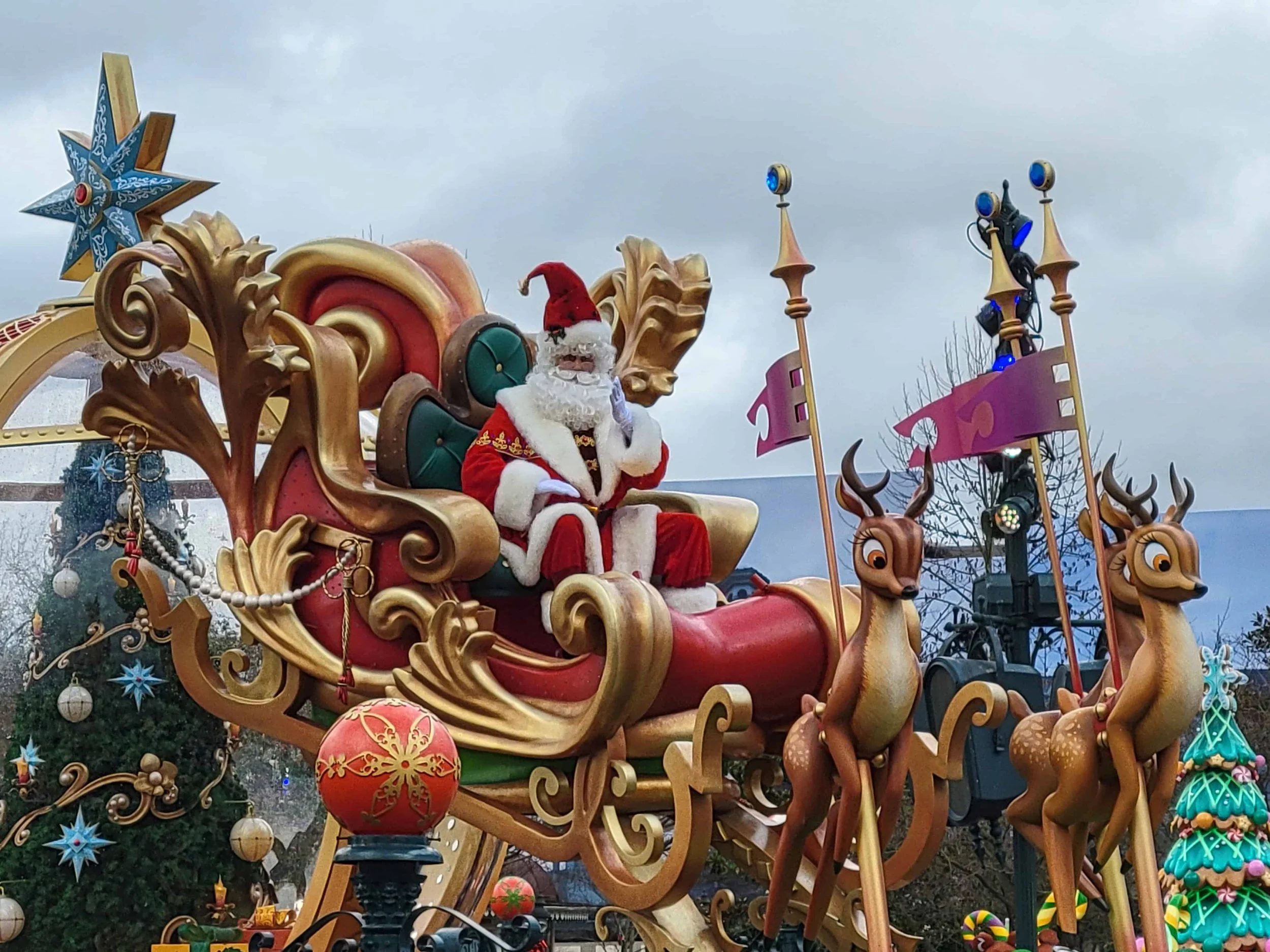 Santa Claus waves from a gold sleigh pulled by reindeer on a float in the Christmas parade at Disneyland Paris.