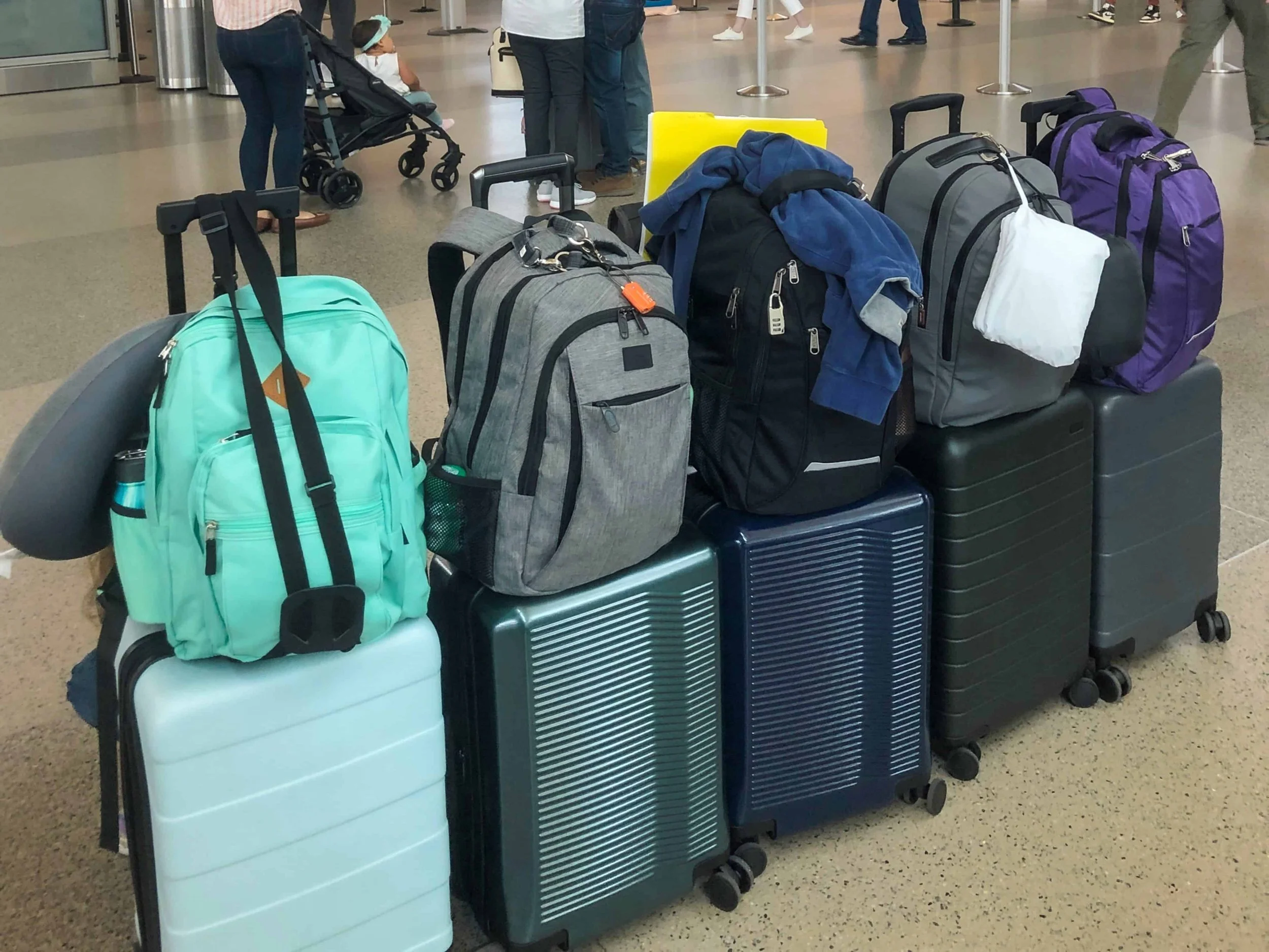A full-time travel family picture of our travel gear consisting of 1 carry-on-size roller bag and 1 backpack each. It makes for cheaper and simpler travel days.