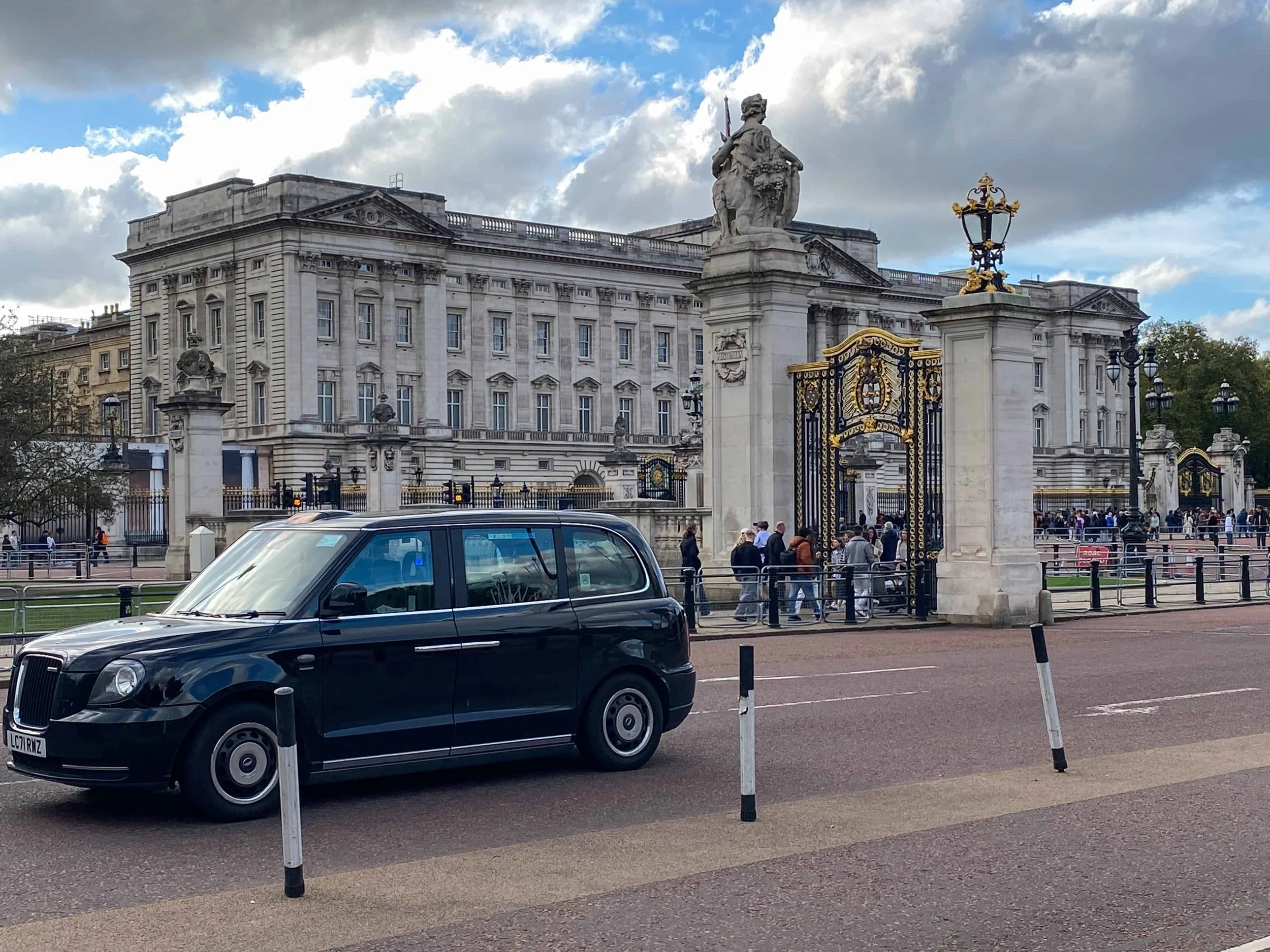 Classic black London taxi driving past Buckingham Palace gates – iconic transport sight in budget family London guide.