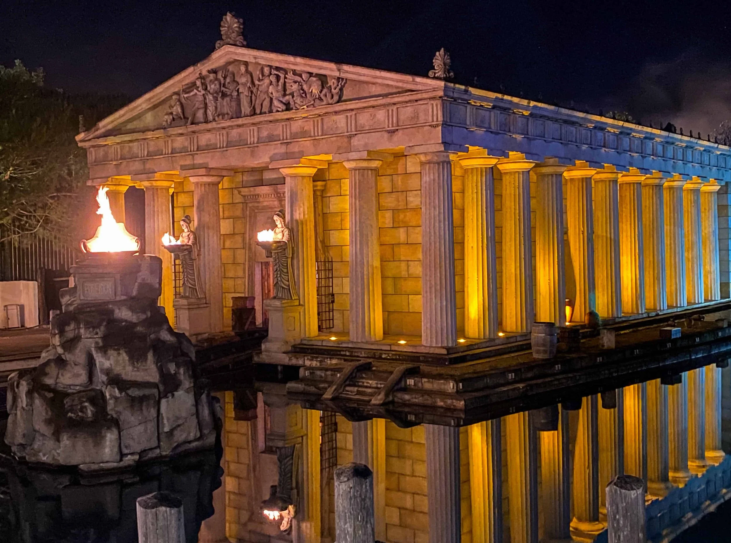 The illuminated Greek-themed temple in Europa-Park’s Greece area, reflected in the water at night.