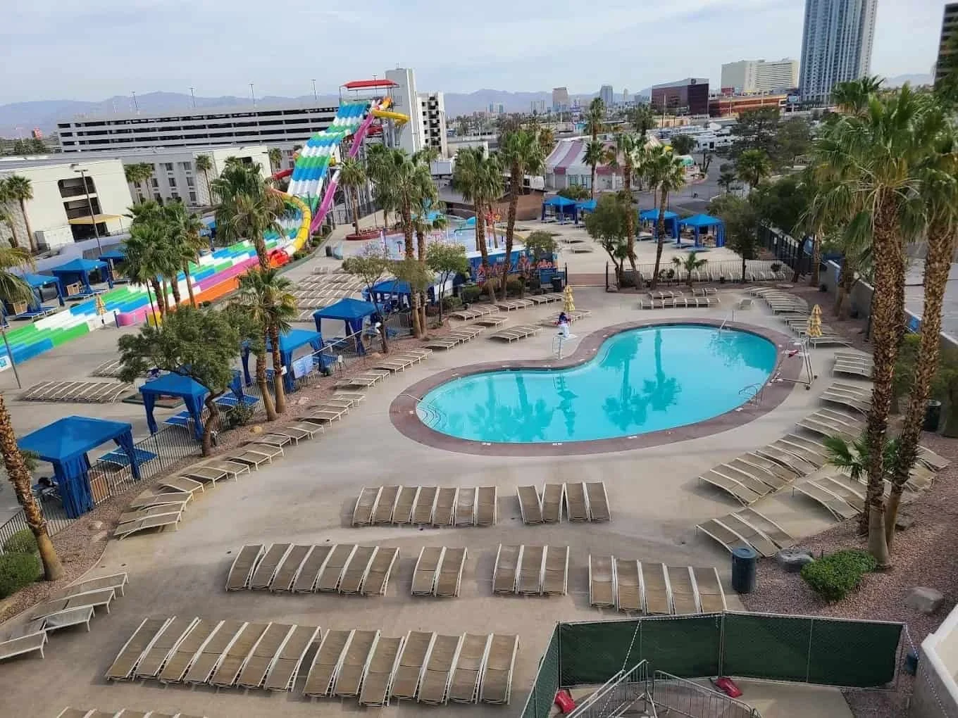 Circus Circus Splash Zone pool with a colorful multi-slide tower, palm trees, and rows of lounge chairs.